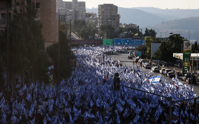 Tens of thousands of demonstrators wave Israeli flags as they march into Jerusalem on July 22, 2023, during a multi-day march that started in Tel Aviv to protest the government's judicial overhaul legislation ahead of a vote on the first such law in the Knesset. (Menahem Kahana / AFP)