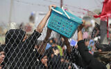 A woman passes a basket of cold water bottles to spectators amid searing heat as Shiite Muslims reenact the Battle of Karbala marking the peak of Ashura, a 10-day period commemorating the seventh century killing of Prophet Mohammed's grandson Imam Hussein, in Sadr City in eastern Baghdad on July 29, 2023. (Photo by Ahmad AL-RUBAYE / AFP)