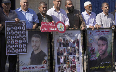 Illustrative: Protesters carry pictures of various Palestinian security prisoners, left and center, who are being held in administrative detention and posters of prisoner Nasser Abu Hmeid, right and second left, who is reported to be critically ill and serving several life sentences and an additional 50 years, during a protest against the Israeli administrative detention policy, in front of the Office of the United Nations High Commissioner for Human Rights in Gaza City, October 12, 2022. Arabic on the red banner reads: “Down with the administrative detention." (AP Photo/Adel Hana)