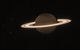 This June 2023 image provided by the Space Telescope Science Institute shows the planet Saturn and three of its moons, from left, Enceladus, Tethys and Dione, captured by the James Webb Space Telescope. In infrared, the planet appears dark because sunlight is absorbed by methane in the atmosphere. (NASA, ESA, CSA, JWST Saturn Team via AP)