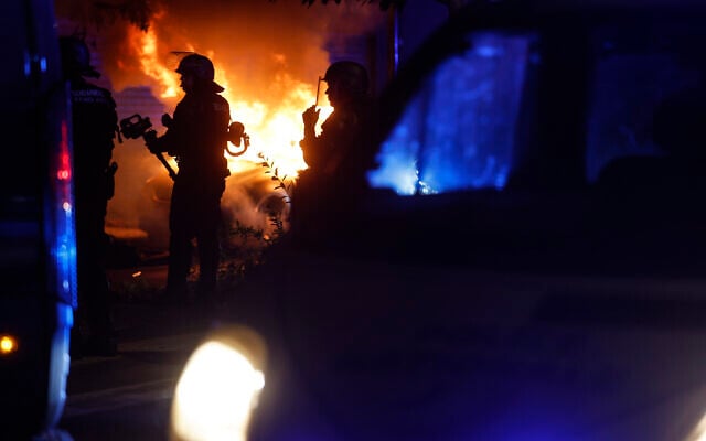 Riot police stand near a burning car in the La Meinau neighborhood of Strasbourg, eastern France, on June 30, 2023 (AP Photo/Jean-Francois Badias)