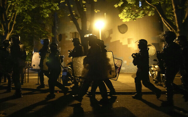 A group of police officers walk during a protest in Nanterre, outside Paris, France, Saturday, July 1, 2023. French President Emmanuel Macron urged parents Friday to keep teenagers at home and proposed restrictions on social media to quell rioting spreading across France over the fatal police shooting of a 17-year-old driver. (AP Photo/Lewis Joly)