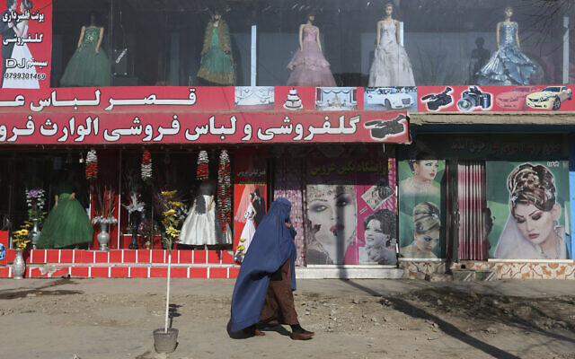 A woman walks past a beauty salon and dress shop in Kabul, Afghanistan, December 13, 2015. (Rahmat Gul/AP)