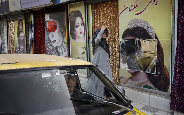 A woman walks past beauty salons with window decorations which have been defaced in Kabul, Afghanistan, September 12, 2021. (Bernat Armangue/AP)