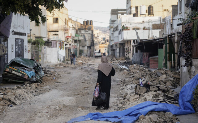 A Palestinian woman walks on a damaged road in the Jenin refugee camp in the West Bank, July 5, 2023, after the Israeli army withdrew its forces from the terror stronghold. (AP Photo/Majdi Mohammed)