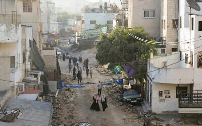 Palestinians walk on a damaged road in the Jenin refugee camp in the West Bank, July 5, 2023, after the Israeli army withdrew its forces from the terror stronghold. (AP Photo/Majdi Mohammed)