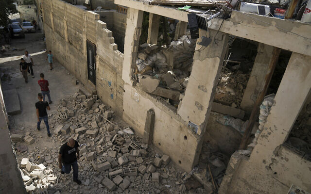 Palestinians walk by a damaged house in the Jenin refugee camp in the West Bank, July 5, 2023, after the Israeli army withdrew its forces from the terror stronghold. (AP Photo/Nasser Nasser)