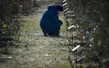 The mother of a Russian soldier who was killed in a military action in Ukraine kneels near a tree planted in memory of her son at the Alley of Heroes in Sevastopol, Crimea, February 25, 2023. (AP Photo)