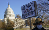 FILE - Protester David Barrows carries a sign during a rally to press Congress to pass voting rights protections and the 'Build Back Better Act,' Dec. 13, 2021, in Washington. (AP Photo/Patrick Semansky, File)