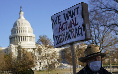 FILE - Protester David Barrows carries a sign during a rally to press Congress to pass voting rights protections and the 'Build Back Better Act,' Dec. 13, 2021, in Washington. (AP Photo/Patrick Semansky, File)