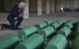 United States Ambassador to Bosnia and Herzegovina Michael J. Murphy kneels next to the coffins containing remains of 30 newly identified victims of the Srebrenica Genocide in Potocari, Bosnia, July 10, 2023. (AP/Armin Durgut)