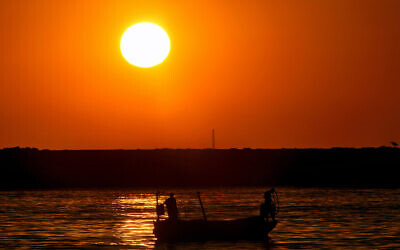 File: Men stand in a boat and fish as the sun sets over the Mediterranean Sea coastline in Beirut, Lebanon, July 12, 2023. (AP Photo/Bilal Hussein)