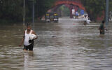 People navigate their way through a flooded street following heavy rainfall in New Delhi, India, Thursday, July 13, 2023. (AP/Manish Swarup)