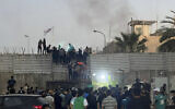 Protesters scale a wall at the Swedish Embassy in Baghdad, July 20, 2023. (AP Photo/Ali Jabar)