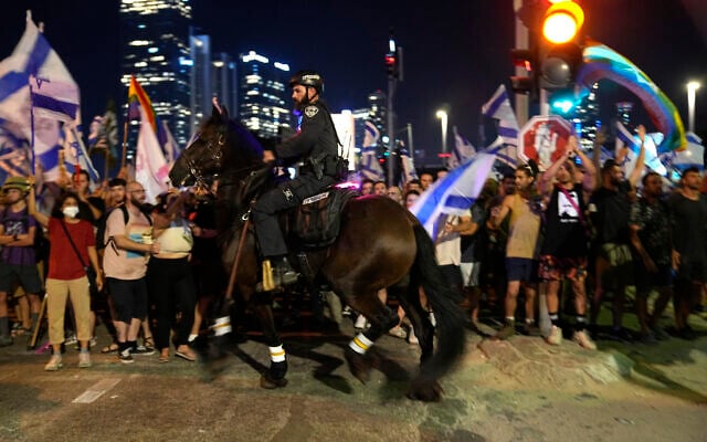 A mounted police officer holds back Israelis protesting against plans by Prime Minister Benjamin Netanyahu's government to overhaul the judicial system, in Tel Aviv, Thursday, July 20, 2023. (AP Photo/Ohad Zwigenberg)