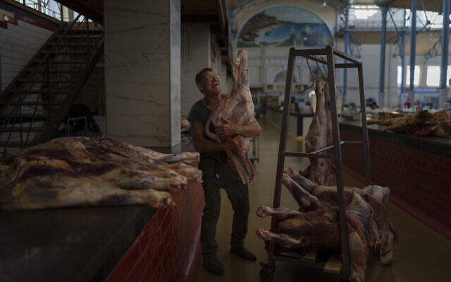 A worker hangs butchered meat on a rack at Privoz Market in Odesa, Ukraine, July 24, 2023. (Jae C. Hong/AP)