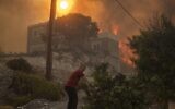 A local pulls a tree branch as a wildfire burns in Gennadi village, on the Aegean Sea island of Rhodes, southeastern Greece, on July 25, 2023. (AP Photo/Petros Giannakouris)