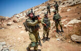Israeli soldiers stand guard while Palestinians and left-wing activists protest in the village of Beit Dajan, in the West Bank, on July 21, 2023. (Nasser Ishtayeh/Flash90)