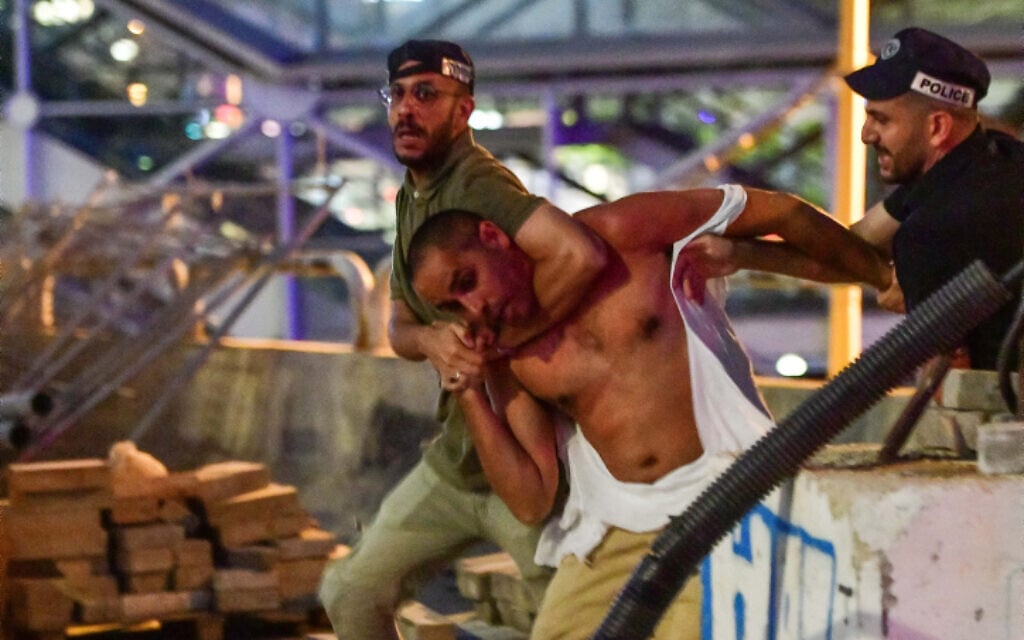 Police officers place a demonstrator in a chokehold during an anti-overhaul protest on the Ayalon Highway in Tel Aviv on July 24, 2023. (Avshalom Sassoni/Flash90)