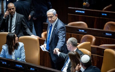 Prime Minister Benjamin Netanyahu shakes hands with Justice Minister Yariv Levin as the Knesset votes to enact the 'reasonableness' law, July 24, 2023. (Yonatan Sindel/Flash90)