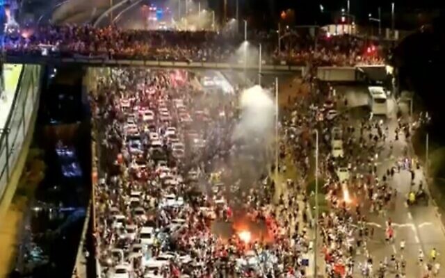 Demonstrators stand amid the traffic as they block the Ayalon Highway during a protest rally against the government's judicial overhaul, in Tel Aviv on July 24, 2023. (Channel 12 screenshot)