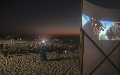 Palestinian children watch a movie at a pop-up open-air cinema at the beach in Gaza City on July 28, 2023; there are no movie theaters in the Gaza Strip. (Photo by Mohammed ABED / AFP)