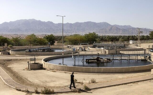 A worker at the Ein Netafim wastewater treatment plant walks past a primary treatment water clarifier basin in Eilat on July 13, 2023. (MENAHEM KAHANA / AFP)