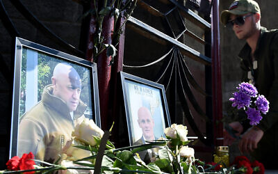 A member of private mercenary group Wagner pays tribute to Yevgeny Prigozhin (L) and Dmitry Utkin, a shadowy figure who managed Wagner's operations and allegedly served in Russian military intelligence, at the makeshift memorial in front of the PMC Wagner office in Novosibirsk, on August 24, 2023. (Photo by Vladimir NIKOLAYEV / AFP)