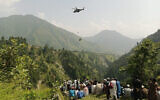 People watch as an army soldier slings down from a helicopter during a rescue mission to recover students stuck in a chairlift in Pashto village of mountainous Khyber Pakhtunkhwa province, on August 22, 2023. (AFP)