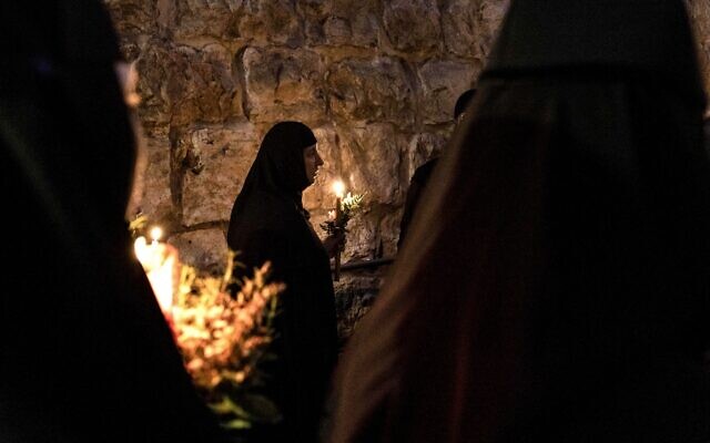 Orthodox nuns hold candles and flowers as they walk along the narrow streets of Jerusalem's Old City in a religious procession marking The Dormition of the Theotokos (God-bearer) which commemorates the Virgin Mary on August 25, 2023. (MENAHEM KAHANA / AFP)