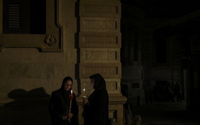 Orthodox nuns hold candles and flowers as they walk along the narrow streets of Jerusalem's Old City in a religious procession marking The Dormition of the Theotokos (God-bearer) which commemorates the Virgin Mary on August 25, 2023. (RONALDO SCHEMIDT / AFP)