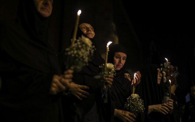 Orthodox nuns hold candles and flowers as they walk along the narrow streets of Jerusalem's Old City in a religious procession marking The Dormition of the Theotokos (God-bearer) which commemorates the Virgin Mary on August 25, 2023. (RONALDO SCHEMIDT / AFP)
