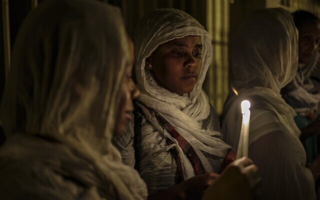 Ethiopian nuns hold candles and flowers as they walk along the narrow streets of Jerusalem's Old City in a religious procession marking The Dormition of the Theotokos (God-bearer) which commemorates the Virgin Mary on August 25, 2023. - Christian Orthodox clergy and pilgrims took part in the early morning procession, an annual event during which Orthodox believers carry an icon of the Virgin Mary from the Church of the Holy Sepulchre to Mary's Tomb Church, located on the foothills of the Mount of Olives, near Gethsemane garden, which is regarded as the burial place of Virgin, according to Christian tradition. (Photo by RONALDO SCHEMIDT / AFP)