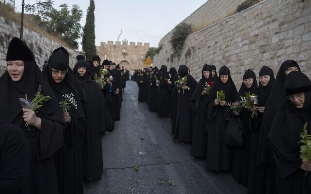 Orthodox nuns hold candles and flowers as they walk along the narrow streets of Jerusalem's Old City in a religious procession marking The Dormition of the Theotokos (God-bearer) which commemorates the Virgin Mary on August 25, 2023. (MENAHEM KAHANA / AFP)