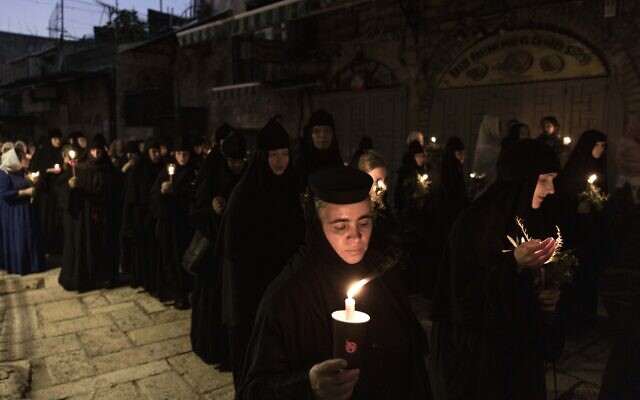 Orthodox nuns hold candles and flowers as they walk along the narrow streets of Jerusalem's Old City in a religious procession marking The Dormition of the Theotokos (God-bearer) which commemorates the Virgin Mary on August 25, 2023. (MENAHEM KAHANA / AFP)