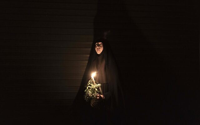 Orthodox nuns hold candles and flowers as they walk along the narrow streets of Jerusalem's Old City in a religious procession marking The Dormition of the Theotokos (God-bearer) which commemorates the Virgin Mary on August 25, 2023. - Christian Orthodox clergy and pilgrims took part in the early morning procession, an annual event during which Orthodox believers carry an icon of the Virgin Mary from the Church of the Holy Sepulchre to Mary's Tomb Church, located on the foothills of the Mount of Olives, near Gethsemane garden, which is regarded as the burial place of Virgin, according to Christian tradition. (Photo by MENAHEM KAHANA / AFP)