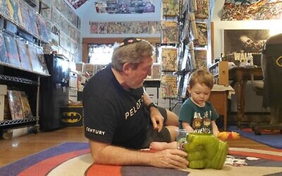 Rabbi Victor Urecki plays with his grandson in his comic book room. (Courtesy Victor Urecki via JTA)
