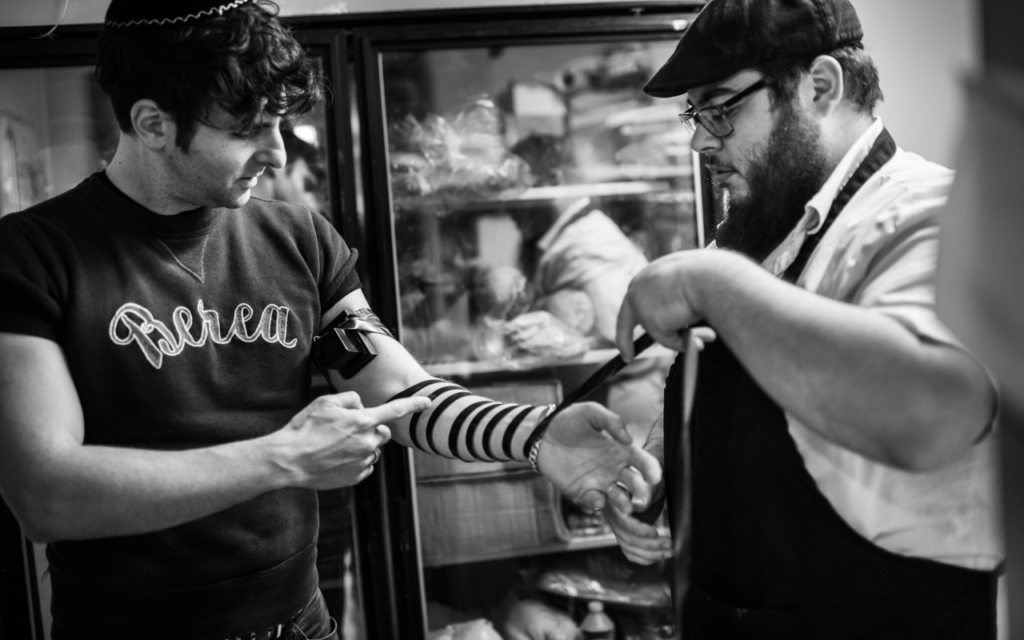 Adam Weiner wraps tefillin on tour. (Jacob Blickenstaff via JTA)