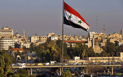 Illustrative: A Syrian national flag waves as vehicles move on a bridge during rush hour, in Damascus, Syria, on Feb. 28, 2016. (Hassan Ammar/AP)