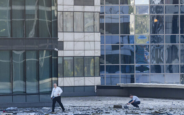 Investigators examine an area next to a damaged building in the "Moscow City" business district after a reported drone attack in Moscow, Russia, early Tuesday, Aug. 1, 2023.
