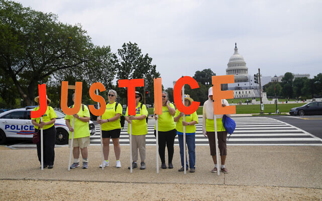Protesters hold signs that spell JUSTICE with the US Capitol in the background, August 3, 2023, in Washington. Former US president Donald Trump was due in federal court to answer to charges that he sought to overturn the results of the 2020 presidential election. (AP Photo/Jess Rapfogel)