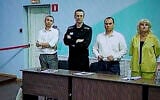 Russian opposition leader Alexei Navalny, 2nd left, is seen on a TV screen standing with his lawyers, as he appears in a video link provided by the Russian Federal Penitentiary Service, during a hearing in the colony, in Melekhovo, Vladimir region, about 260 kilometers (163 miles) northeast of Moscow, Russia, on August 4, 2023. (AP Photo/ Alexander Zemlianichenko)