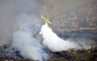 An aircraft drops water over a fire in Apesia, a semi-mountainous village near Limassol, southwestern Cyprus, August 7, 2023. (Philippos Christou/AP) An aircraft drops water over a fire in Apesia, a semi-mountainous village near Limassol, southwestern Cyprus, August 7, 2023. (Philippos Christou/AP)