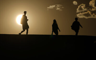 FILE - People walk along a trail as the sun sets, July 16, 2023, in Death Valley National Park, California (AP Photo/John Locher, File)