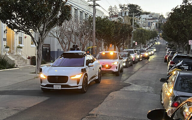 A Waymo driverless taxi stops on a street in San Francisco for several minutes because the back door was not completely shut, while traffic backs up behind it, on February 15, 2023. (AP Photo/Terry Chea, file)