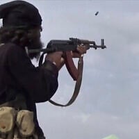 This file frame grab from video posted online March 18, 2019, by the Aamaq News Agency, a media arm of the Islamic State group, shows an IS fighter firing his weapon during clashes with the US-backed Syrian Democratic Forces (SDF) fighters, in Baghouz, Syria. (Aamaq News Agency via AP, File)