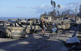 A woman walks through wildfire wreckage Friday, August 11, 2023, in Lahaina, Hawaii. (AP Photo/Rick Bowmer)