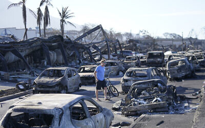 A man walks through wildfire wreckage on August 11, 2023, in Lahaina, Hawaii. (AP Photo/Rick Bowmer)