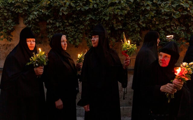 Christian orthodox nuns hold candles and flowers as they walk in a procession to bring an icon of the Virgin Mary to the tomb where it is believed she is buried, along the streets of the Old City of Jerusalem, early Friday, Aug. 25, 2023. Every year before the Feast of the Assumption, the icon is brought from the Church of the Holy Sepulchre to the tomb of the Virgin Mary to honor her Assumption. (AP/Ohad Zwigenberg)