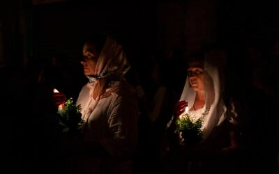 Christian orthodox women hold candles and flowers as they walk in a procession to bring an icon of the Virgin Mary to the tomb where it is believed she is buried, along the streets of the Old City of Jerusalem, early Friday, Aug. 25, 2023. Every year before the Feast of the Assumption, the icon is brought from the Church of the Holy Sepulchre to the tomb of the Virgin Mary to honor her Assumption. (AP/Ohad Zwigenberg)